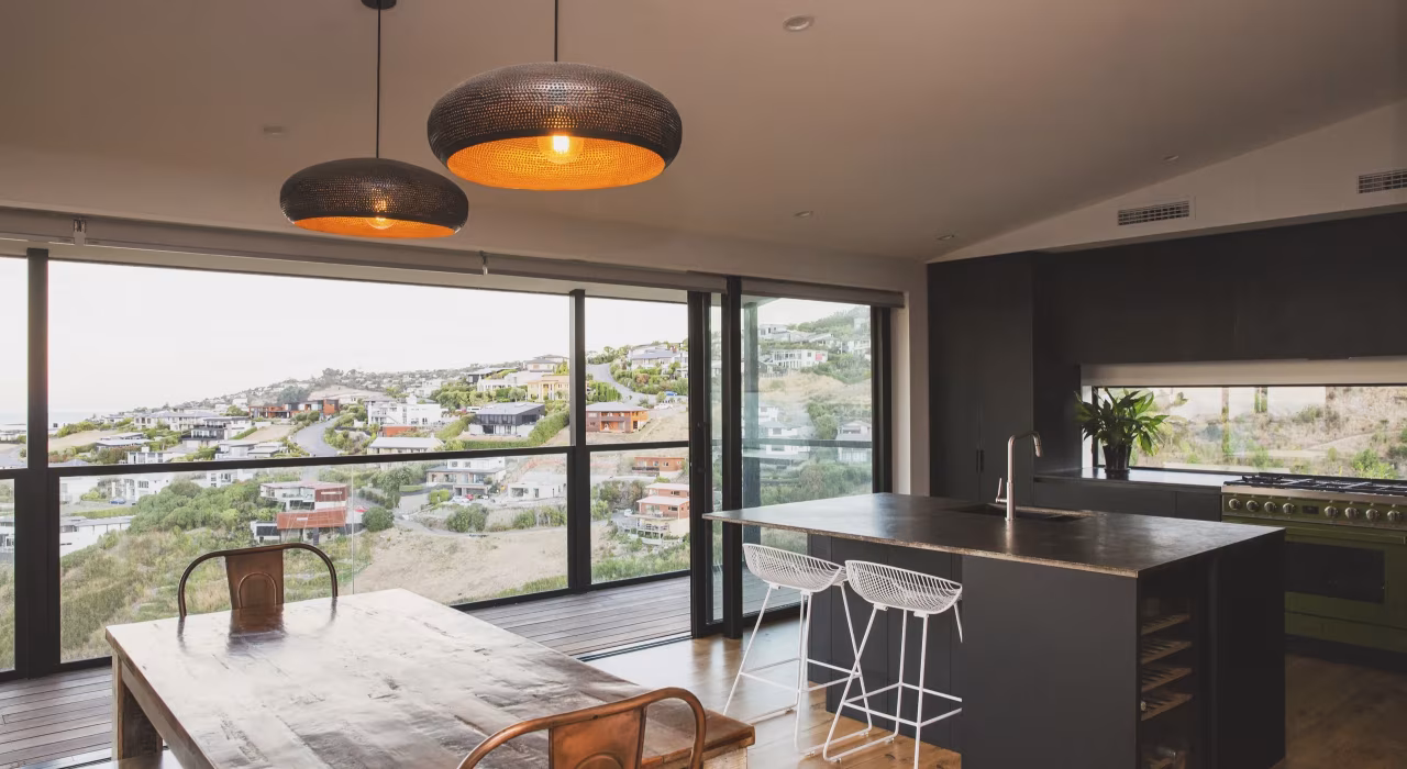 <img alt="Open-plan kitchen and dining with pendant lighting and full-height glazing framing views over the surrounding hills." src="/images/s/i/t/e/-/site-architecture-drayton-drive6-46772bc0.webp" width="2560" height="1706" />